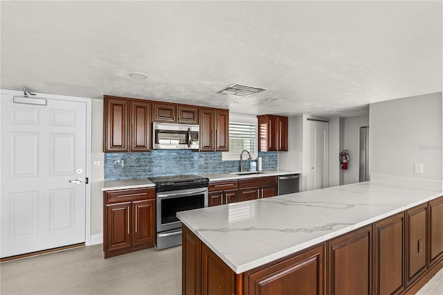 kitchen featuring stainless steel appliances, light stone countertops, sink, and kitchen peninsula