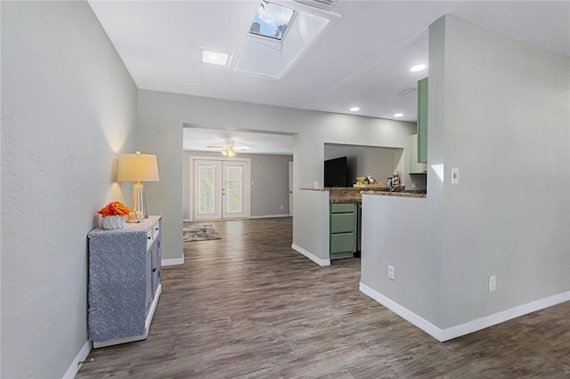 interior space featuring ceiling fan, a skylight, and hardwood / wood-style floors