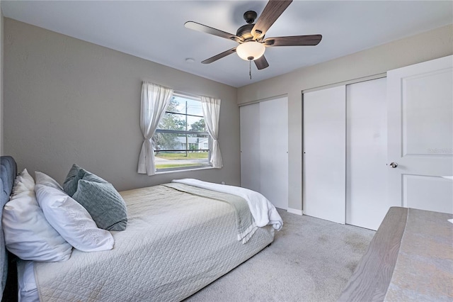 carpeted bedroom featuring ceiling fan and two closets