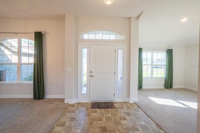 entryway featuring baseboards, a healthy amount of sunlight, and light colored carpet