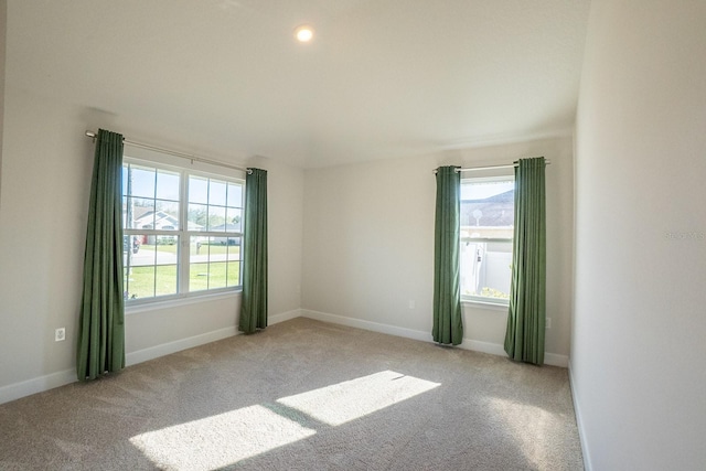 spare room featuring baseboards, a healthy amount of sunlight, and light colored carpet