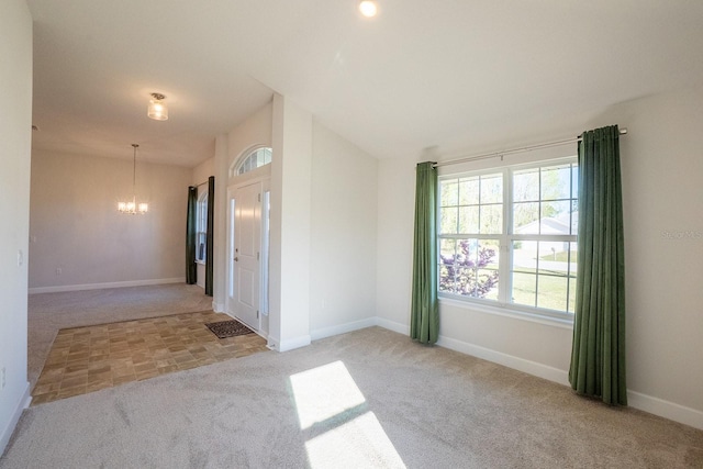 spare room with light carpet, baseboards, and an inviting chandelier