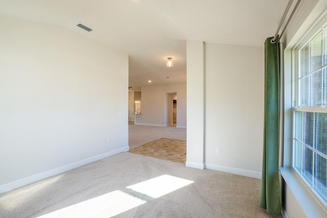 unfurnished room with carpet floors, baseboards, and visible vents