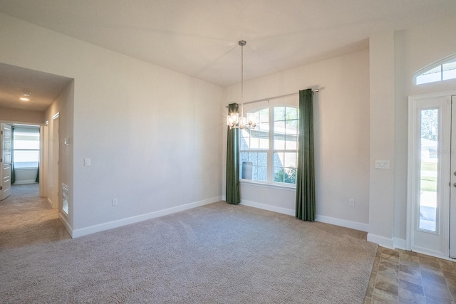 carpeted spare room with baseboards and a notable chandelier