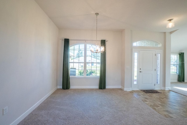 foyer entrance with baseboards, carpet floors, and a notable chandelier