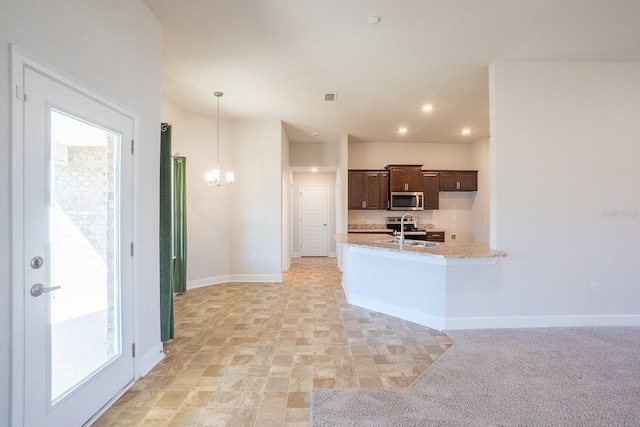 kitchen featuring a notable chandelier, stainless steel microwave, a sink, dark brown cabinets, and baseboards