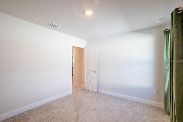 carpeted spare room with a textured ceiling, visible vents, and baseboards