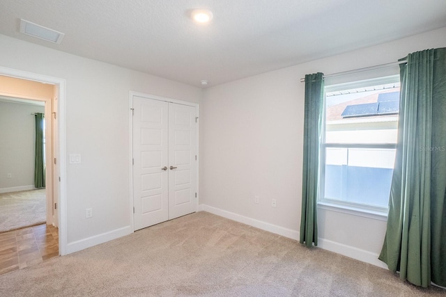 unfurnished bedroom with a closet, carpet, visible vents, and baseboards