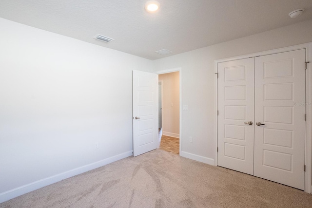 unfurnished bedroom featuring visible vents, baseboards, a textured ceiling, carpet floors, and a closet