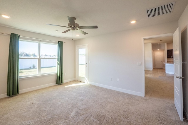 spare room featuring light colored carpet, visible vents, baseboards, and recessed lighting