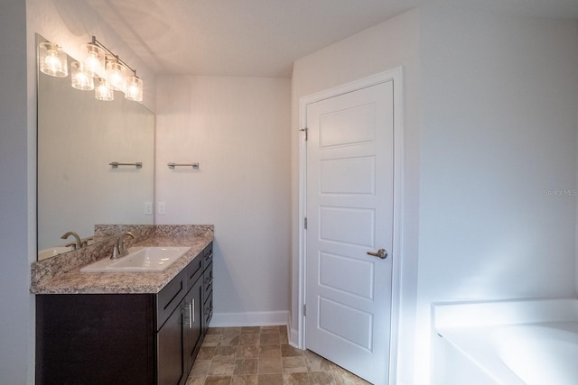 bathroom featuring a washtub, vanity, and baseboards