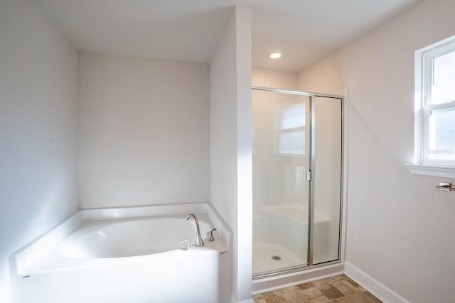 full bath featuring a stall shower, a garden tub, and baseboards