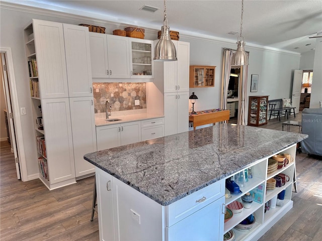 kitchen featuring open shelves, dark wood-style floors, visible vents, and a sink