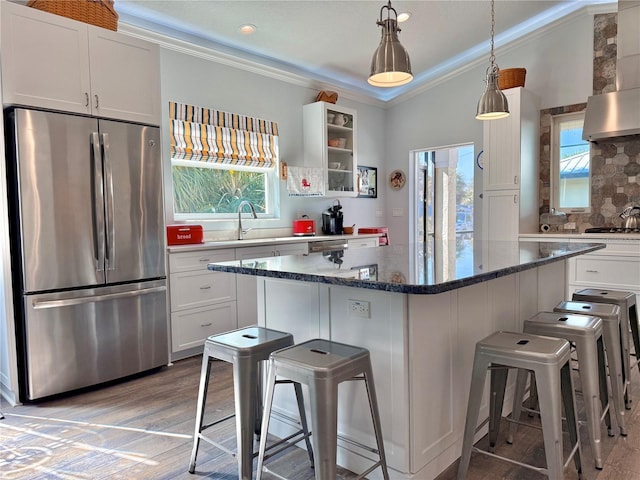 kitchen featuring ornamental molding, a kitchen breakfast bar, freestanding refrigerator, white cabinetry, and a sink