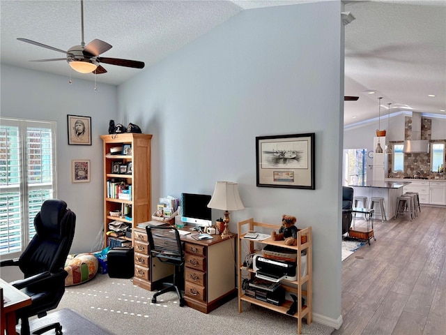 office area featuring light wood finished floors, a textured ceiling, a ceiling fan, and vaulted ceiling