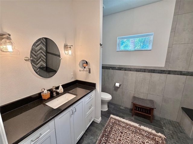 bathroom with toilet, tile walls, and vanity