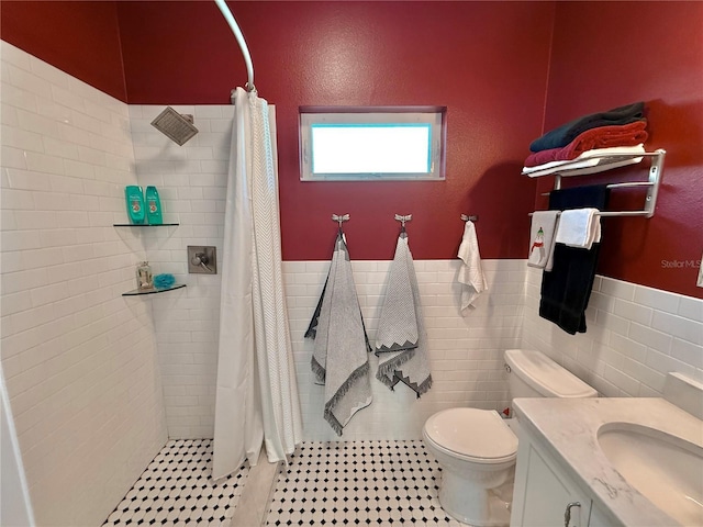 bathroom with a tile shower, a wainscoted wall, toilet, and tile walls