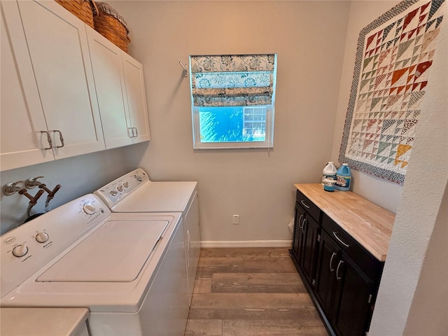 clothes washing area with wood finished floors, cabinet space, independent washer and dryer, and baseboards