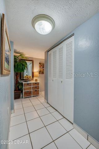 corridor with a textured ceiling and light tile patterned floors