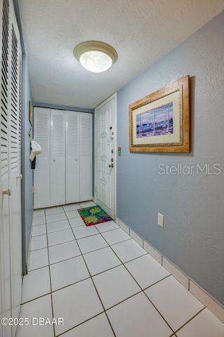 doorway to outside featuring light tile patterned flooring and a textured ceiling