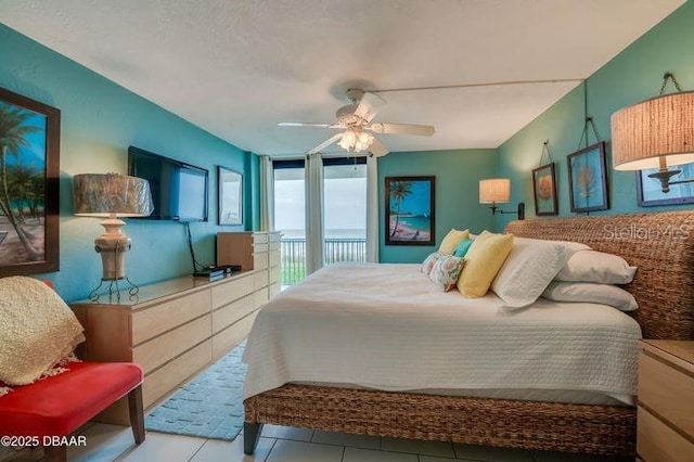 tiled bedroom with access to outside, ceiling fan, and a wall of windows