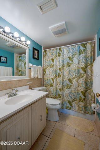 bathroom featuring tile patterned floors, toilet, vanity, and tile walls