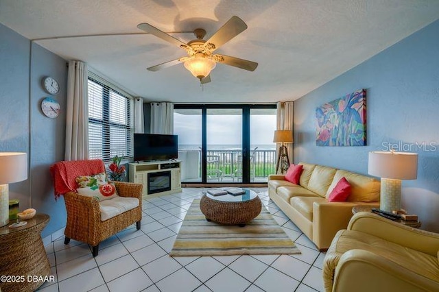 living room featuring expansive windows, ceiling fan, light tile patterned flooring, and a textured ceiling