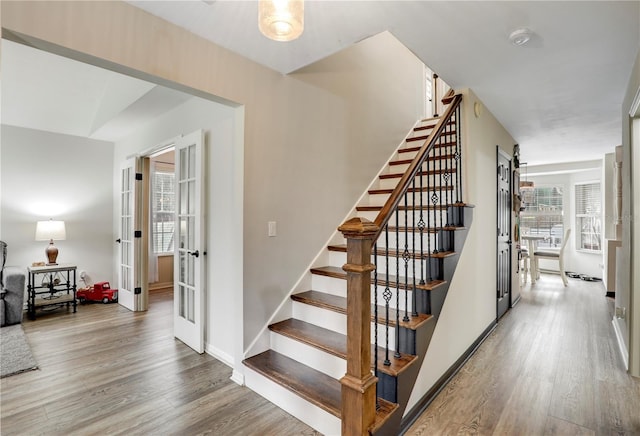 staircase featuring french doors, baseboards, and wood finished floors