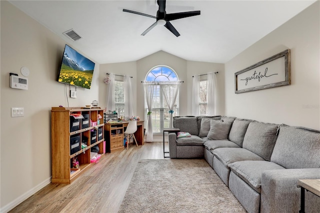 living area with light wood finished floors, visible vents, vaulted ceiling, ceiling fan, and baseboards