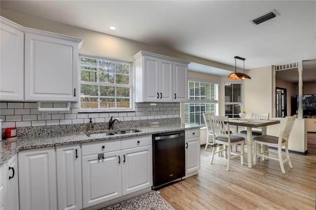 kitchen featuring pendant lighting, black dishwasher, visible vents, white cabinets, and a sink