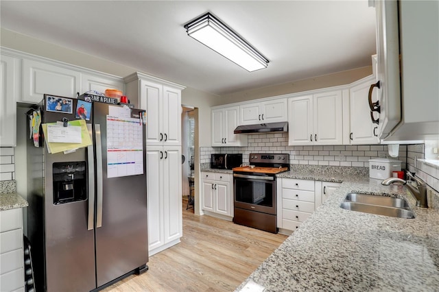 kitchen featuring white cabinets, light stone countertops, stainless steel appliances, under cabinet range hood, and a sink