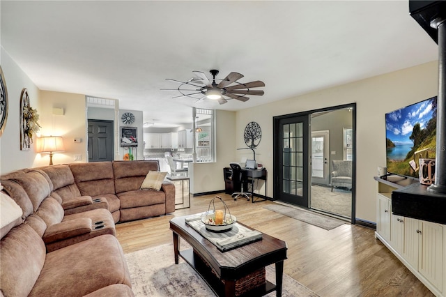 living area with ceiling fan, french doors, light wood-style flooring, and baseboards