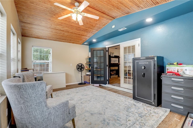 living area featuring light wood finished floors, lofted ceiling, a ceiling fan, wooden ceiling, and baseboards