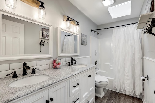 full bath featuring a skylight, a sink, shower / tub combo, and wood finished floors