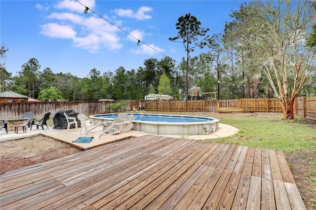 view of swimming pool featuring a fenced in pool, a patio, a lawn, a deck, and a fenced backyard