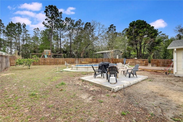 view of yard featuring a fenced backyard, a fenced in pool, a playground, and a patio