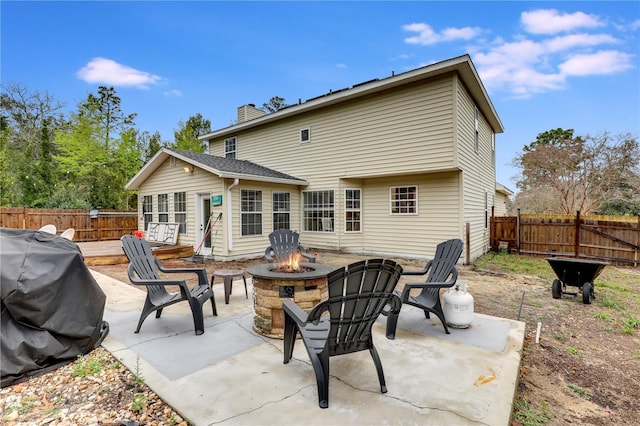 back of property featuring an outdoor fire pit, fence, a chimney, and a patio