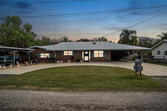 view of front of property with metal roof, an attached carport, brick siding, a yard, and concrete driveway