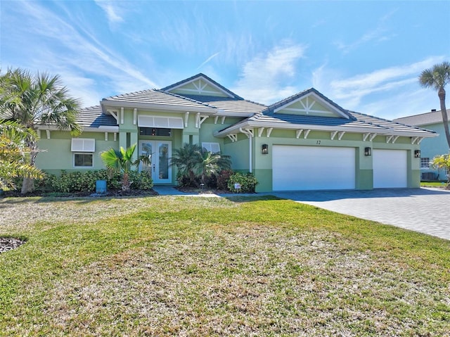 view of front of house featuring a front yard, a tile roof, an attached garage, and stucco siding