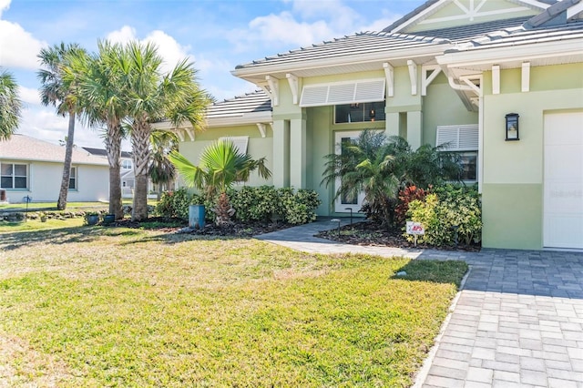 view of front of home with a garage, a front yard, a tile roof, and stucco siding