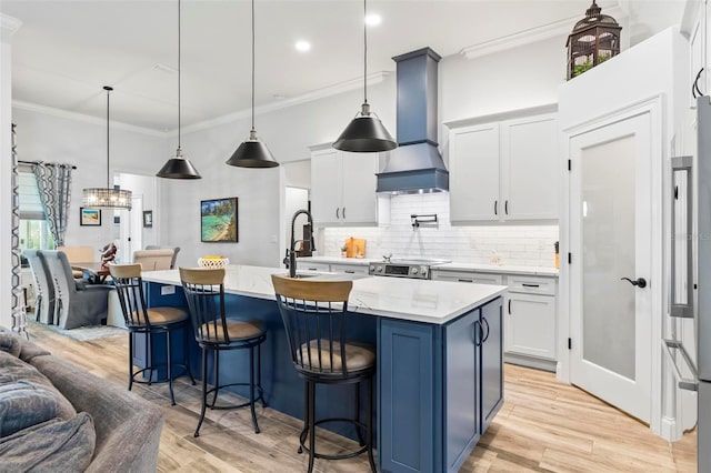 kitchen with light wood-type flooring, wall chimney exhaust hood, ornamental molding, and backsplash