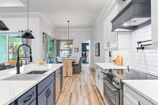 kitchen with a sink, white cabinets, custom range hood, appliances with stainless steel finishes, and crown molding