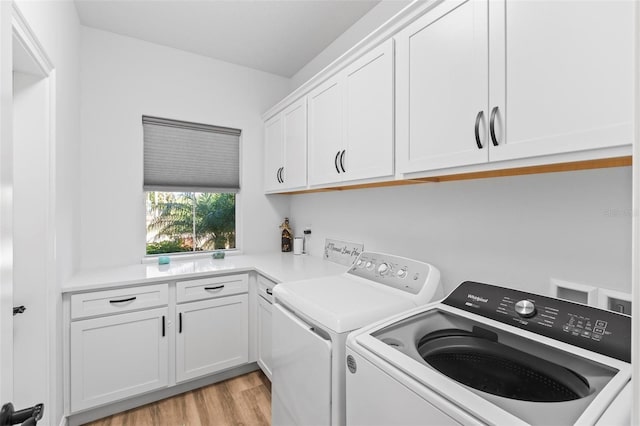 clothes washing area featuring light wood-style flooring, cabinet space, and washer and dryer