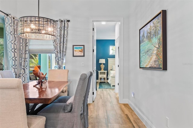 dining room featuring light wood-style flooring, baseboards, and an inviting chandelier