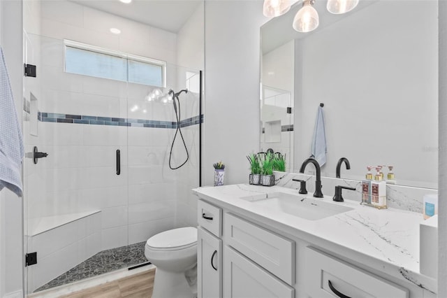 bathroom featuring toilet, a shower stall, wood finished floors, and vanity