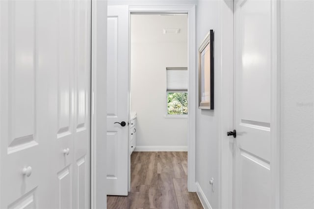 corridor featuring wood finished floors and baseboards