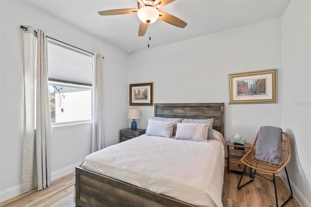 bedroom featuring a ceiling fan, light wood-style flooring, and baseboards