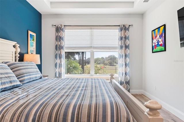 bedroom featuring wood finished floors, visible vents, and baseboards