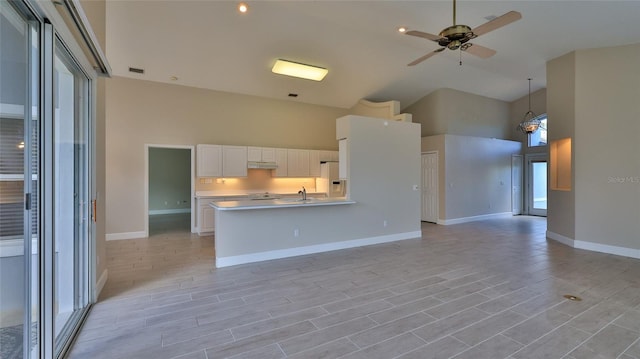 kitchen featuring white cabinetry, white fridge with ice dispenser, a towering ceiling, hanging light fixtures, and light hardwood / wood-style flooring