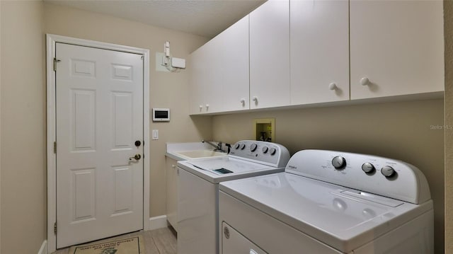 clothes washing area with sink, cabinets, and washer and dryer